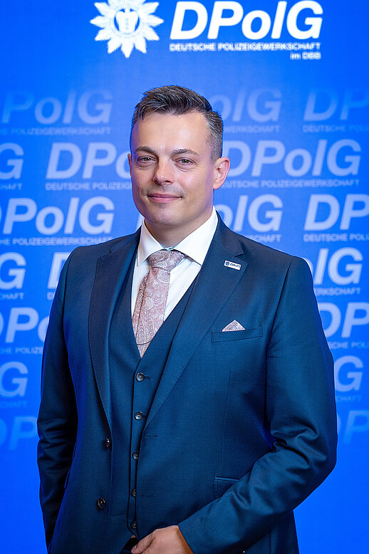 Frank Teichert, neuer Landesvorsitzender der DPolG Berlin, beim 25. Landeskongress 2026 vor einer blauen DPolG-Fotowand.