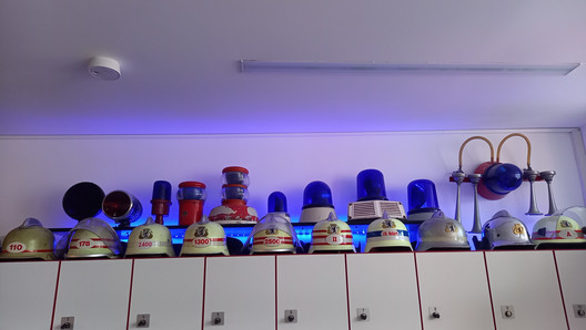 diverse Blaulichter und Helme der Feuerwehr auf einem Schrank