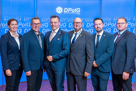 Der neu gewählte Landesvorstand der DPolG Berlin beim 25. Landeskongress gemeinsam mit dem scheidenden Landesvorsitzenden Bodo Pfalzgraf vor einer DPolG-Fotowand.