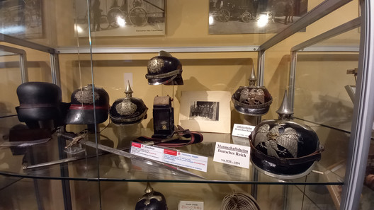 Mehrere historische Feuerwehrhelme in einer Vitrine